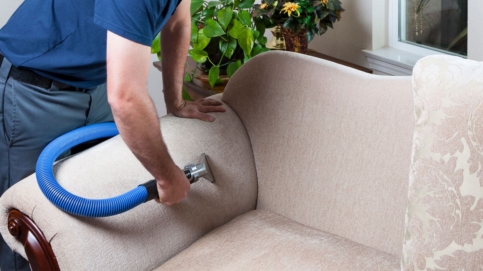 Technician cleaning a fabric sofa with an upholstery tool
